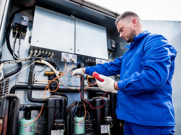 Technician servicing commercial refrigeration system outdoors